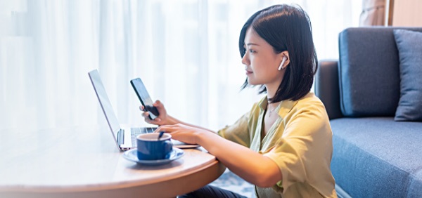 Woman at her laptop while using phone